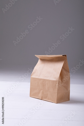 Close-up of brown paper lunch bag on table against gray background with copy space
