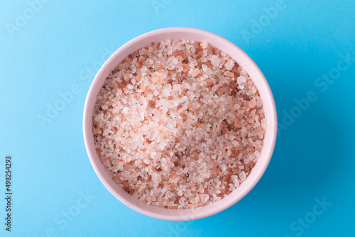 Close up view of sea salt in a bow with copy space on blue background