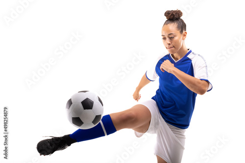 Fototapeta Naklejka Na Ścianę i Meble -  Biracial young female player kicking soccer ball while playing soccer against white background