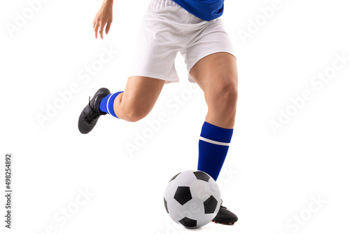 Low section of biracial young female soccer player kicking soccer ball against white background