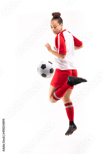Fototapeta Naklejka Na Ścianę i Meble -  Full length of biracial young female player kicking soccer ball with back heel while playing soccer