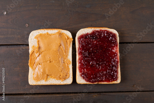 Directly above shot of bread slices with peanut butter and preserves on wooden table