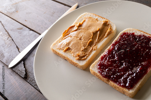 Close-up of preserves and peanut butter on bread slices served in plate at table with table knife