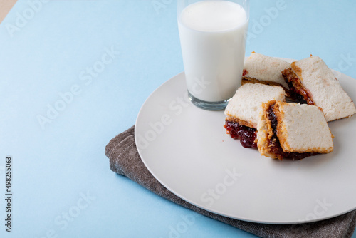 High angle view of peanut butter and jelly sandwich slices served with milk glass in plate on table