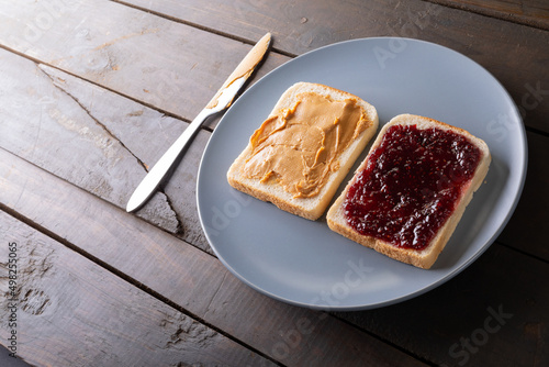 High angle view of open face peanut butter and jelly sandwich in plate on table with table knife