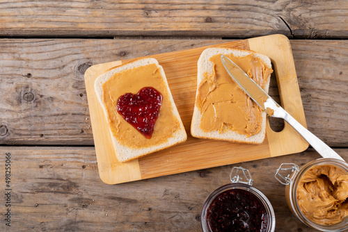 Close-up of open face peanut butter and jelly sandwich on serving board with jars at table