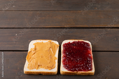 High angle close-up of bread slices with peanut butter and preserves on wooden table