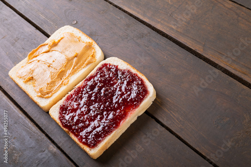 High angle view of bread slices with peanut butter and preserves on wooden table