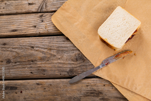 High angle view of peanut butter and jelly sandwiches with table knife on brown paper at table