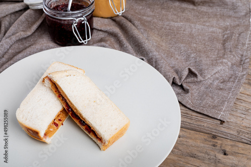 High angle view of peanut butter and jelly sandwich served in plate by jars on napkin at table