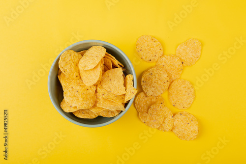 Directly above shot of chips in bowl and on yellow background