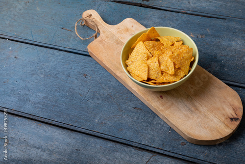 High angle view of nacho chips in bowl on serving board at wooden table