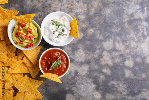 Directly above shot of nacho chips with various dipping sauces served on table