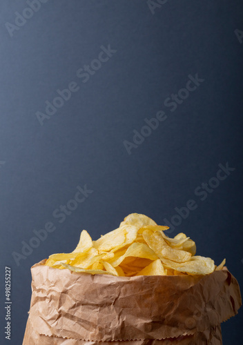 Potato chips in paper bag against gray background with copy space