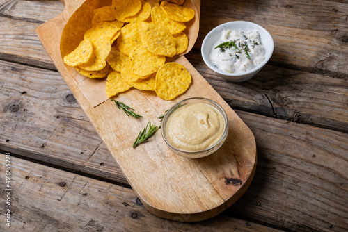 High angle view of crunchy chips with two dipping sauces served on serving board at table