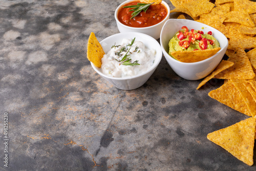Close-up of nacho chips with various dipping sauces served on table