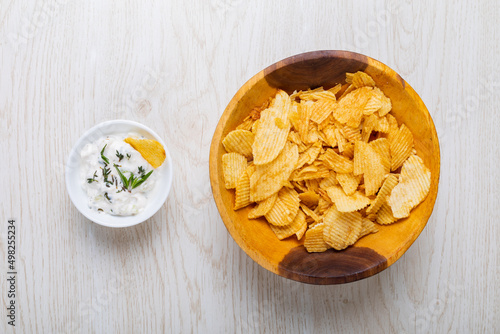 Directly above shot of white dipping sauce with herbs served by potato chips in bowl on table