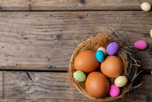 Close-up of easter eggs with colorful candies in nest on wooden table