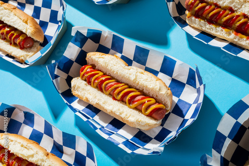 High angle close-up of hot dogs in containers arranged on blue background
