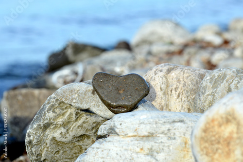 Heart shape stone against background of beach. Summer sunny day. Love, wedding and Valentine day concept. Finding beautiful and interesting stones. Beach vacation. 