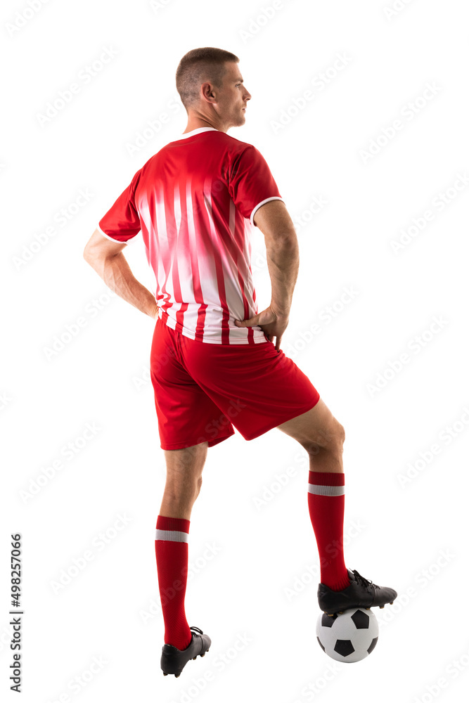 Full length rear view of young male soccer player stepping on ball over white background