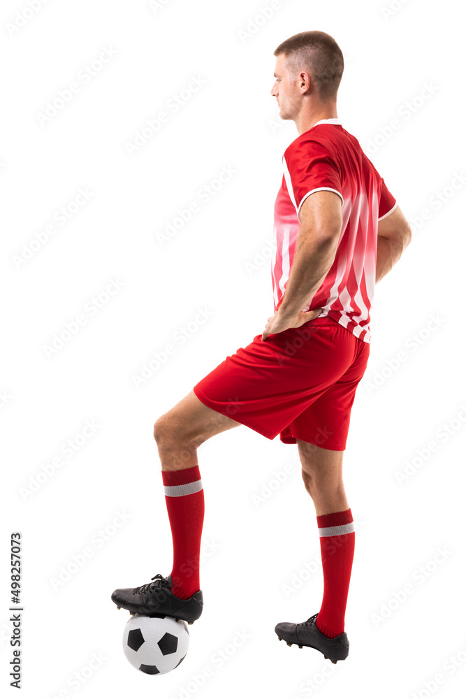 Full length side view of young male caucaisan soccer player stepping on ball over white background