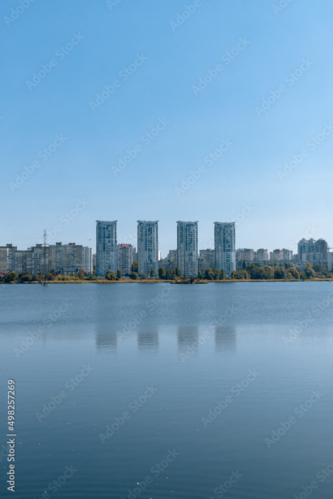 A city on the shore of a wide lake. A river and tall buildings on the far bank