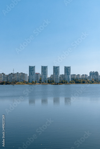 A city on the shore of a wide lake. A river and tall buildings on the far bank