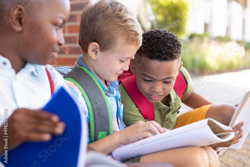 African american elementary schoolboy looking male classmates studying at school entrance