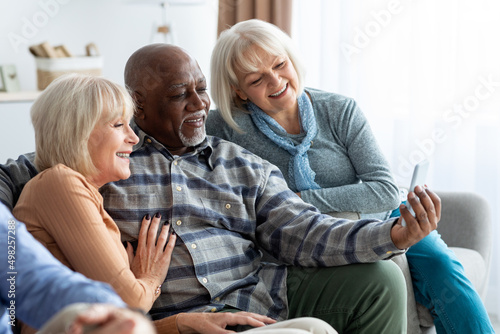 Multiracial group of pensioners using mobile phone