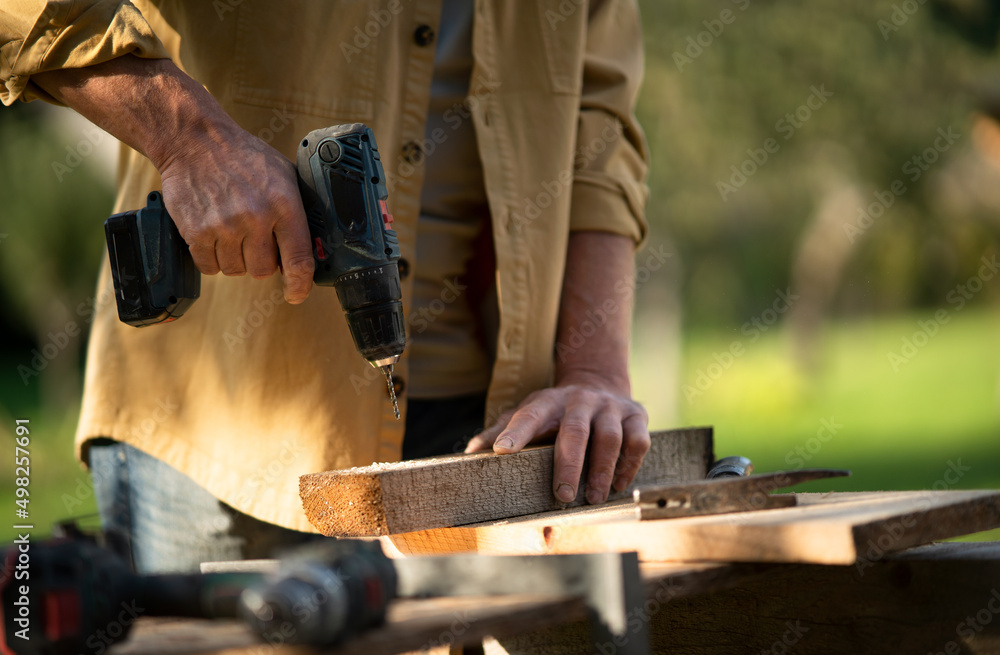 Close-up of handyman carpenter working in carpentry diy workshop outdoors with drill. Close-up of handyman carpenter working in carpentry diy workshop outdoors with drill.