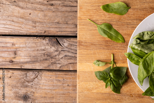 Overhead view of fresh baby spinach on wooden cutting board at table