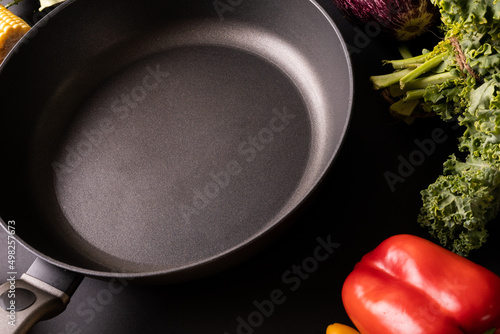 Close-up of black empty frying pan by kale and red bell pepper on table