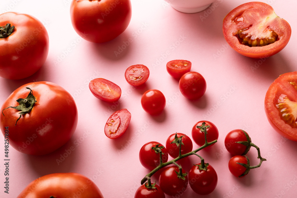 High angle view of fresh tomatoes and cherry tomatoes on pink background High angle view of fresh tomatoes and cherry tomatoes on pink background