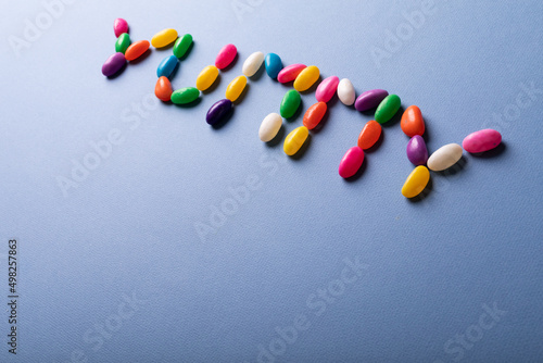 High angle view of colorful yummy word arranged from candies over copy space on blue background