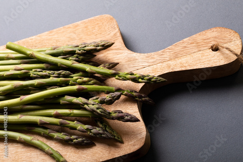 High angle view of fresh green asparagus on wooden cutting board over gray background