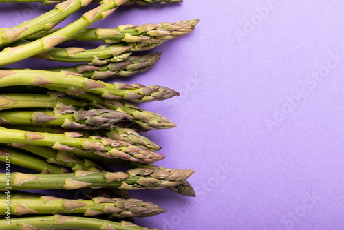 Directly above close-up view of raw asparagus by copy space against purple background