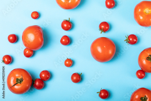 Overhead view of fresh tomatoes scattered over blue background