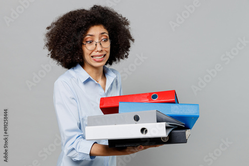 Print op canvas Young sad unhappy employee business corporate lawyer woman of African American ethnicity in formal shirt work in office hold pile of folder for papers document bookkeeping isolated on grey background