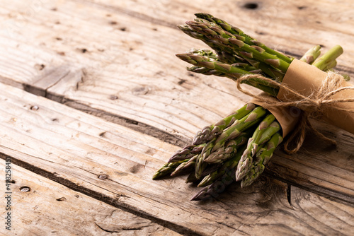 High angle view of raw asparagus vegetables tied with strings on wooden brown table