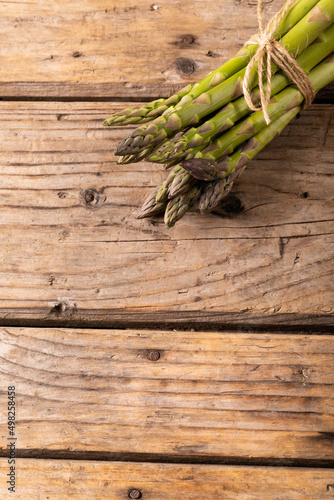Overhead view of string tied raw green asparagus bunches on wooden brown table