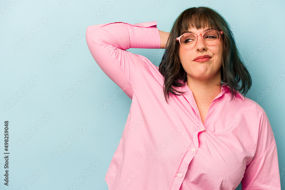 Young caucasian woman isolated on blue background touching back of head, thinking and making a choice. Young caucasian woman isolated on blue background touching back of head, thinking and making a choice.
