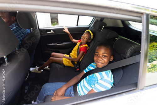 Portrait of smiling african american brother and sister with seat belts traveling in car