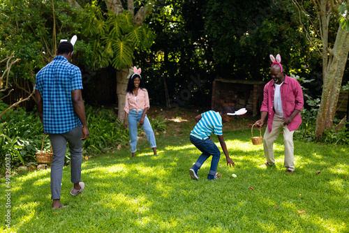Plauful african american multigenerational family in bunny ears with in backyard on easter day