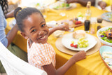 Portrait of smiling african american cute girl having lunch with family at home on thanksgiving day