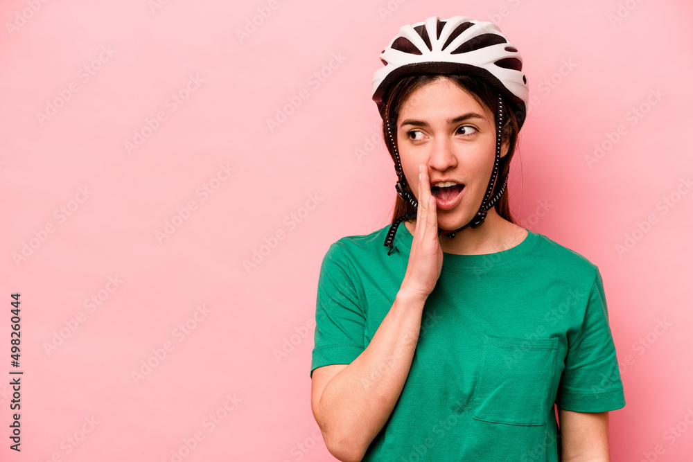 Young caucasian woman wearing helmet isolated on pink background is saying a secret hot braking news and looking aside Young caucasian woman wearing helmet isolated on pink background is saying a secret hot braking news and looking aside