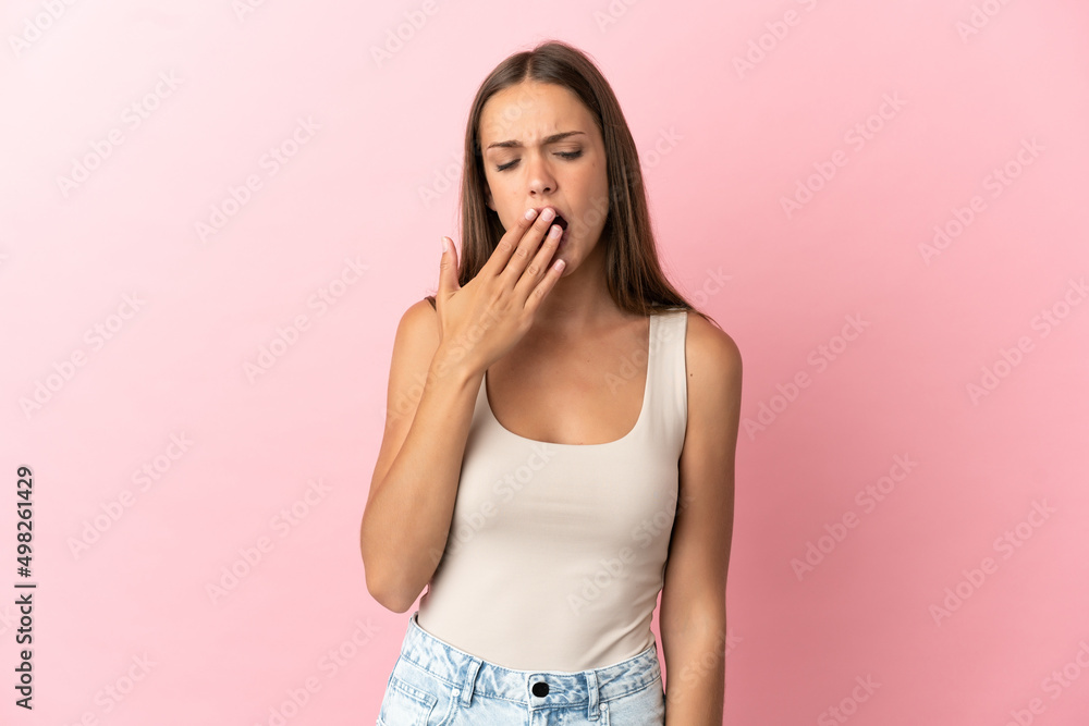 Young woman over isolated pink background yawning and covering wide open mouth with hand Young woman over isolated pink background yawning and covering wide open mouth with hand