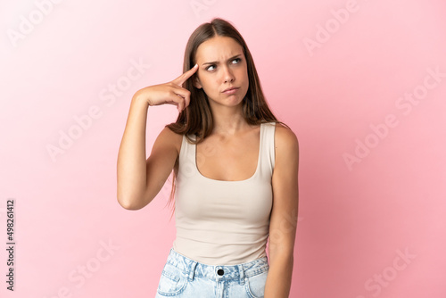 Young woman over isolated pink background making the gesture of madness putting finger on the head photo