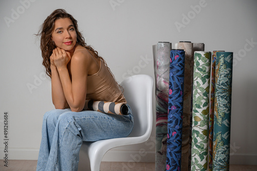 Beautiful young woman with rolls of wallpaper