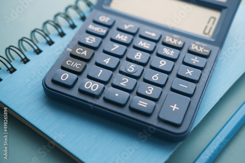 Close up of blue calculator and notepad on color background 